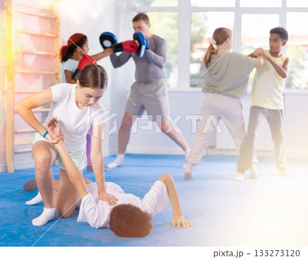 Girl practicing painful armlock in sparring with boy at self defence training 133273120