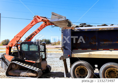 Bobcat machinery moves soil into dump truck during construction work Bobcat machinery moves soil into dump truck during construction work 133273497