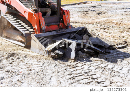 Construction machine operates on site, moving broken concrete debris during renovation work Construction machine operates on site, moving broken concrete debris during renovation work 133273501