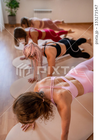 Three women are practicing downward dog variations emphasizing focus and balance in energetic Three women are practicing downward dog variations emphasizing focus and balance in energetic 133273547