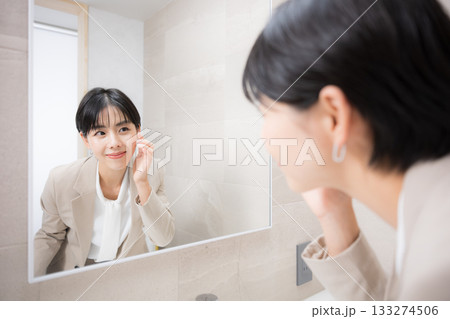 鏡の前で笑顔で身だしなみを整える女性の美容、メイク直しなどのシーン 鏡の前で笑顔で身だしなみを整える女性の美容、メイク直しなどのシーン 133274506