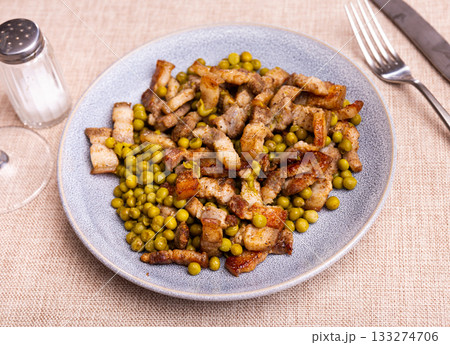 Pieces of fried pork belly with green peas closeup Pieces of fried pork belly with green peas closeup 133274706