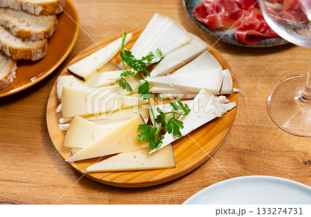 Light snack - slices of manchego cheese on plate 133274731