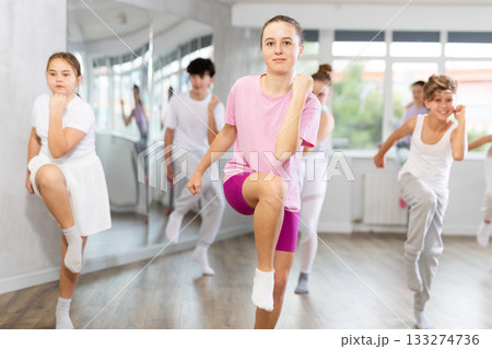 Woman teacher in background dances with students, inspects and observes skill of dancers 133274736