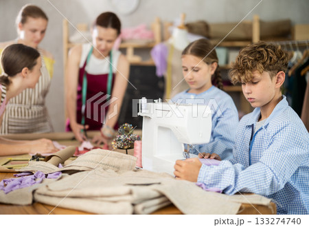 Preteen boy working at machine during group sewing course for kids Preteen boy working at machine during group sewing course for kids 133274740