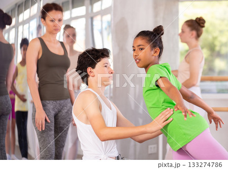 Teenage girl practicing ballet positions in pair with boy in dance studio Teenage girl practicing ballet positions in pair with boy in dance studio 133274786