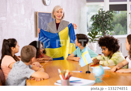 Female teacher showing swedish flag to kids in geography class Female teacher showing swedish flag to kids in geography class 133274851