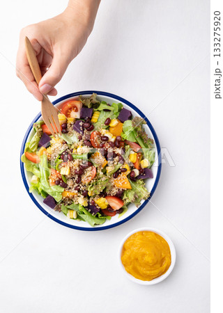 Healthy vegetable salad bowl eating with pumpkin dressing. Vegan and plant-based food Healthy vegetable salad bowl eating with pumpkin dressing. Vegan and plant-based food 133275920