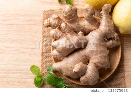 Fresh ginger and lemon on wooden background, Table top view Fresh ginger and lemon on wooden background, Table top view 133275938