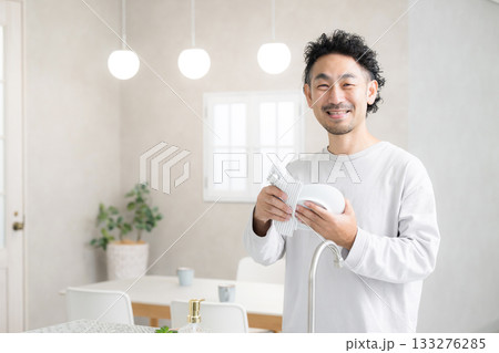 明るいキッチンで笑顔で食器を拭く男性の家事シーン カメラ目線 明るいキッチンで笑顔で食器を拭く男性の家事シーン カメラ目線 133276285