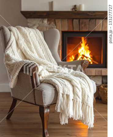 暖炉のそばの椅子に掛けられた、温かそうなニットのブランケット 133277727