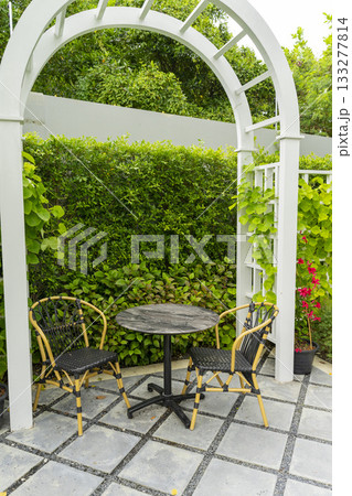 Wooden chairs and table in a beautiful garden canopy in home landscaped garden in summer. Wooden chairs and table in a beautiful garden canopy in home landscaped garden in summer. 133277814
