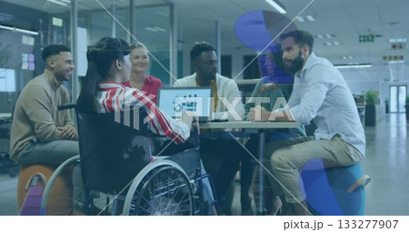 Six office professionals collaborating around meeting table in office, with laptop and wheelchair 133277907