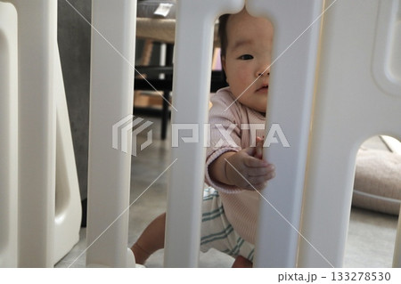 ベビーゲート越しにこちらを覗く0歳の赤ちゃんの様子。 ベビーゲート越しにこちらを覗く0歳の赤ちゃんの様子。 133278530