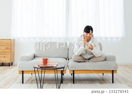 部屋でくつろぎながらスマホを触る女性 133278541