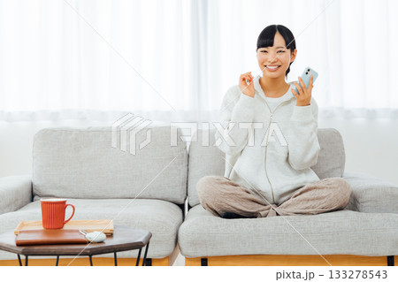 部屋でくつろぎながらスマホを触る女性 133278543