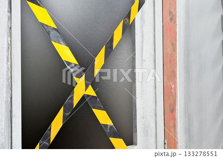 Old door criss crossed by yellow and black tape. Old door criss crossed by yellow and black tape. 133278551
