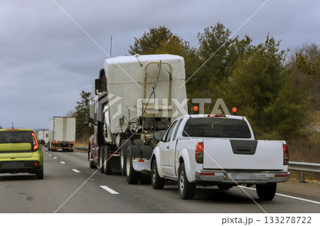 Multiple vehicles, including large truck smaller white pickup, travel down busy American highway Multiple vehicles, including large truck smaller white pickup, travel down busy American highway 133278722