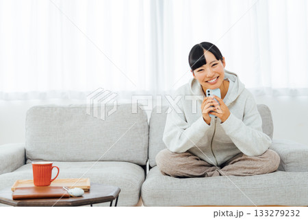 部屋でくつろぎながらスマホを触る女性 133279232