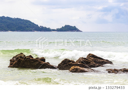 Rocky beach with rocks waves turquoise water in Patong Thailand. Rocky beach with rocks waves turquoise water in Patong Thailand. 133279433
