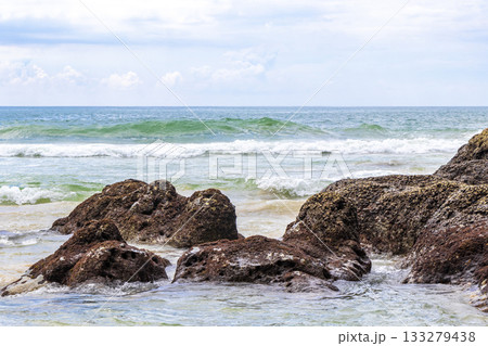 Rocky beach with rocks waves turquoise water in Patong Thailand. Rocky beach with rocks waves turquoise water in Patong Thailand. 133279438