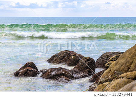 Rocky beach with rocks waves turquoise water in Patong Thailand. Rocky beach with rocks waves turquoise water in Patong Thailand. 133279441