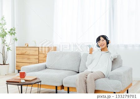 部屋でくつろぎながら音楽を聴く女性 133279701