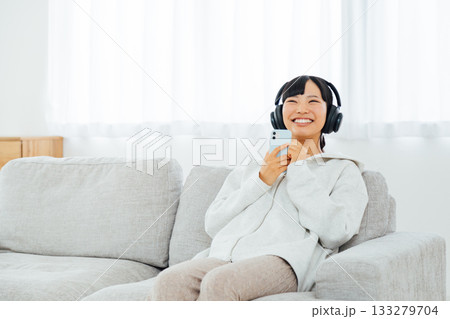 部屋でくつろぎながら音楽を聴く女性 133279704