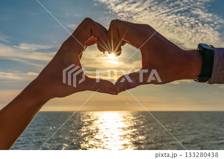 Hands heart sunset ocean view silhouette showing sunburst effect over sparkling water during golden hour Hands heart sunset ocean view silhouette showing sunburst effect over sparkling water during golden hour 133280438
