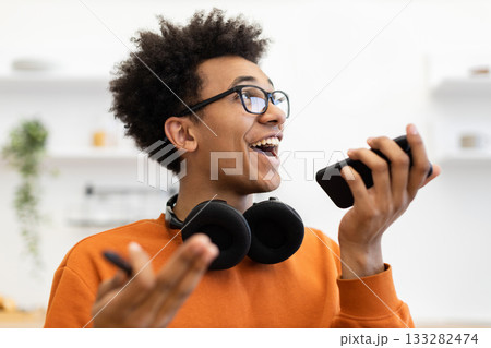 A young man with glasses is talking on his phone, looking happy and engaged. A young man with glasses is talking on his phone, looking happy and engaged. 133282474