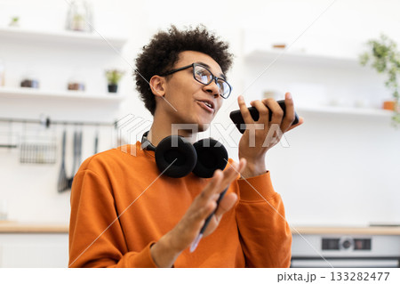 A young man with glasses is talking on his phone, gesturing with his hands. A young man with glasses is talking on his phone, gesturing with his hands. 133282477