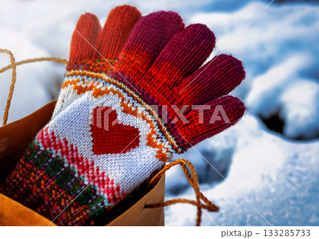 雪の背景 ペーパーギフトバッグに赤基調のカラフルなハートマーク北欧風デザインの手編みの手袋 133285733