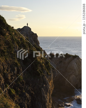 朝焼けの伊良湖防備衛所跡から断崖絶壁に佇む人を臨む 133286888