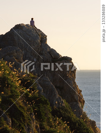 朝焼けの伊良湖防備衛所跡から断崖絶壁に佇む人を臨む 133286889