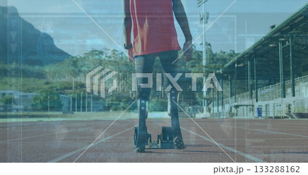 Standing teenage male athlete wearing red top, prosthetic blades on red track with starting blocks Standing teenage male athlete wearing red top, prosthetic blades on red track with starting blocks 133288162