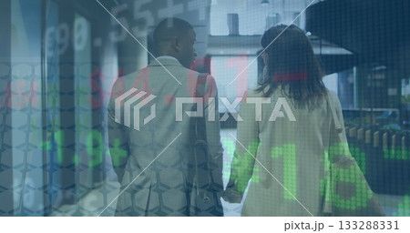 Walking business couple in suits holding hands in corridor carrying bag, with stock market overlay 133288331