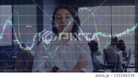Standing woman wearing white shirt and smartwatch observing colleagues at office, financial overlay Standing woman wearing white shirt and smartwatch observing colleagues at office, financial overlay 133288339
