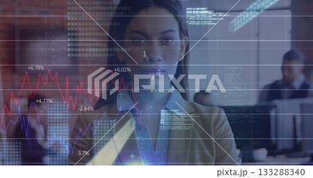 Displaying female business professional visualizing financial charts in open office, with monitors 133288340