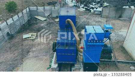 Two large blue machines sitting on metal tracks in scrap yard, with corrugated hose and pallets Two large blue machines sitting on metal tracks in scrap yard, with corrugated hose and pallets 133288405