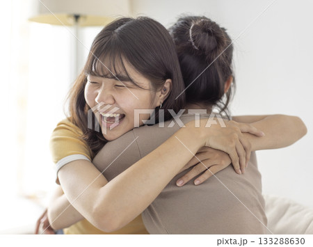 Happy asian girls embraced in a friendly hug Happy asian girls embraced in a friendly hug 133288630