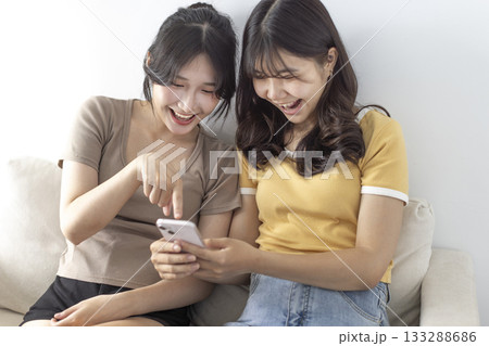 Happy young student girls watching the smartphone Happy young student girls watching the smartphone 133288686