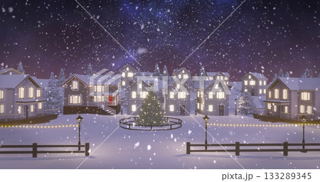 Standing Christmas tree glowing in village square at night, with fences with lights and lampposts 133289345