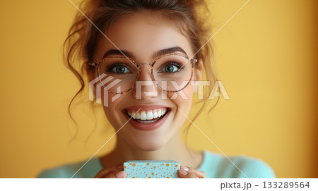 Young woman smiling with glasses holding gift box, joyful lifestyle portrait concept 133289564