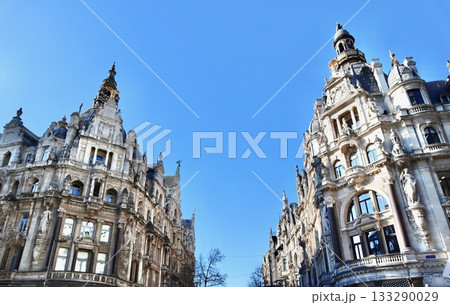 Ornate architecture adorning two historic buildings in Antwerp city center, featuring facades, turrets, and intricate details under a bright sky 133290029