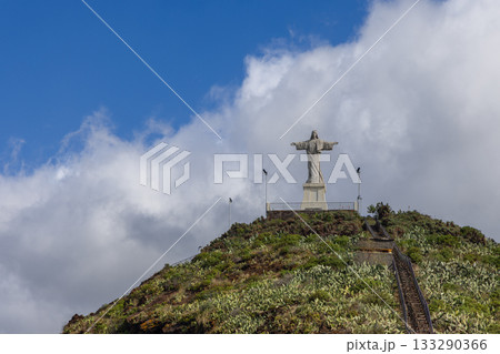 Christ the King statue in Garajau stands above green hill with cactus under drifting white clouds 133290366