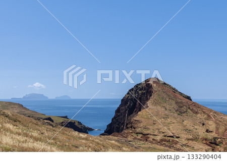 Dry volcanic hill at Sao Lourenco with hikers on summit trail above calm sea and islands 133290404