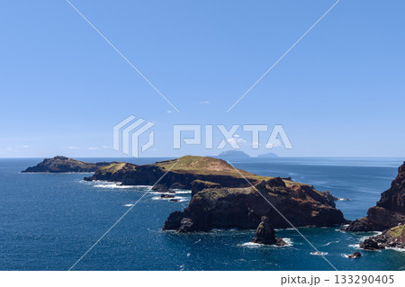 Sao Lourenco cliffs and bright slopes meet deep blue Atlantic with foam and island horizon Sao Lourenco cliffs and bright slopes meet deep blue Atlantic with foam and island horizon 133290405