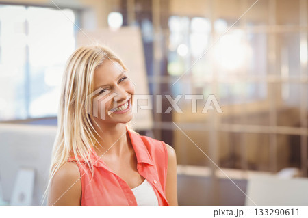 Female office professional standing and smiling in modern glass-walled office with flip chart 133290611