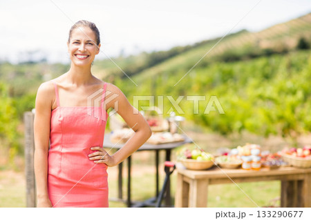 Smiling female in coral dress standing in vineyard with baskets of apples and pastries, copy space Smiling female in coral dress standing in vineyard with baskets of apples and pastries, copy space 133290677
