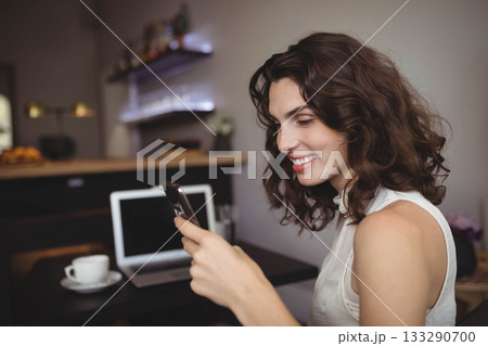 Woman holding smartphone and typing on laptop at cafe bar counter with coffee cup, copy space 133290700